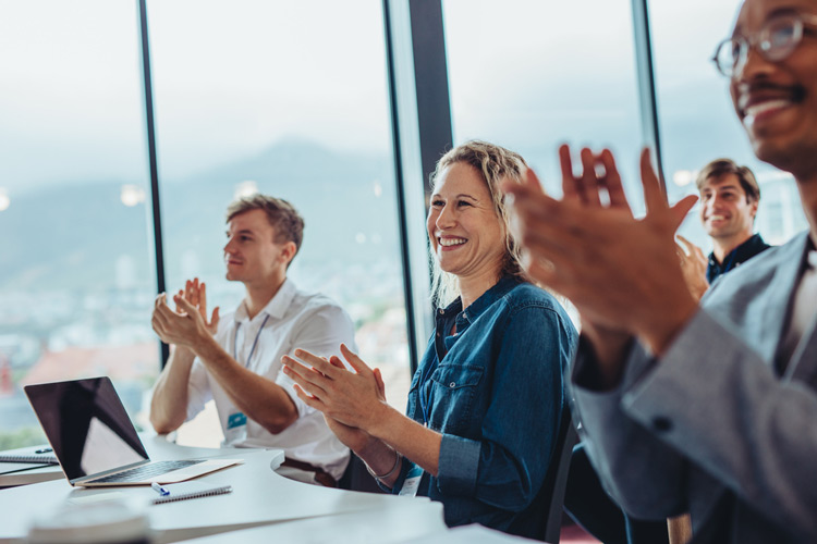 A group of professionals clap after a presentation giving during a conference with SONIFI's Wi-Fi network