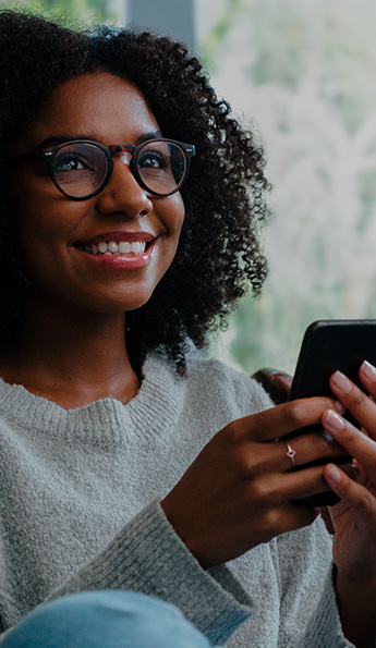 A woman holds her mobile device while watching SONIFI's interactive TV.