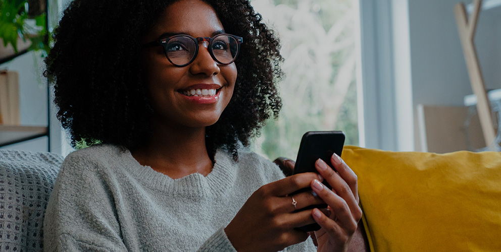 A black woman with glasses uses her mobile phone to control SONIFI's interactive TV in her hotel room