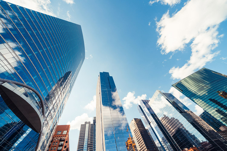 A graphic image taken from the ground around skyscrapers looking up at a blue sky